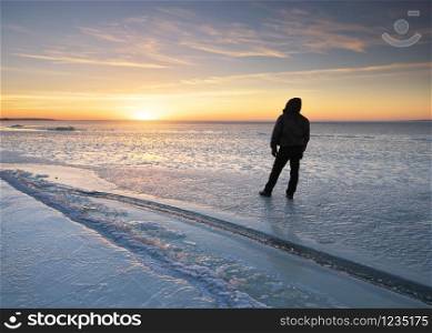Winter landscape and man looking on sunset. Ice blocks. Composition of nature.