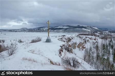 Winter landscape in the valley near the hill. Winter landscape, Orthodox cross on top of a hill