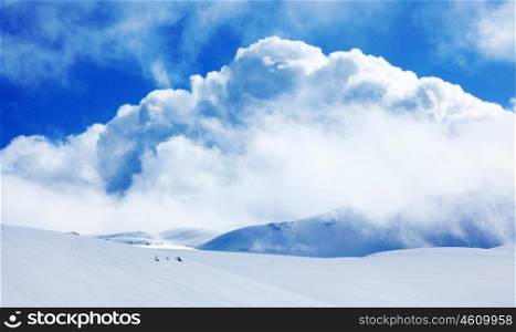 Winter landscape of high mountains with snow blizzard and fresh blue sky, beautiful nature panoramic background