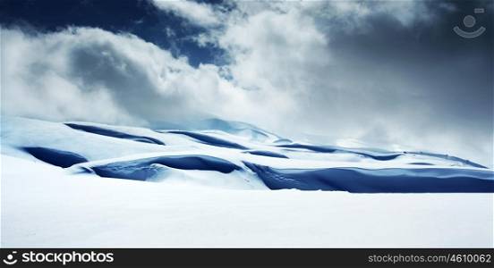 Winter landscape of high mountains with snow blizzard and fresh blue sky, beautiful nature panoramic background