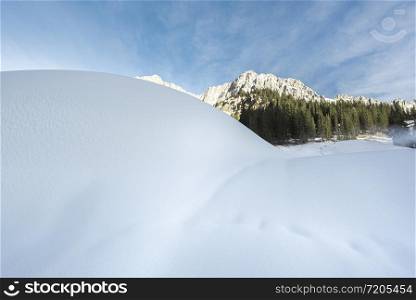 Winter landscape with fresh fluffy snow on a sunny December day. Alpine scenery with snowdrifts and snowy mountains