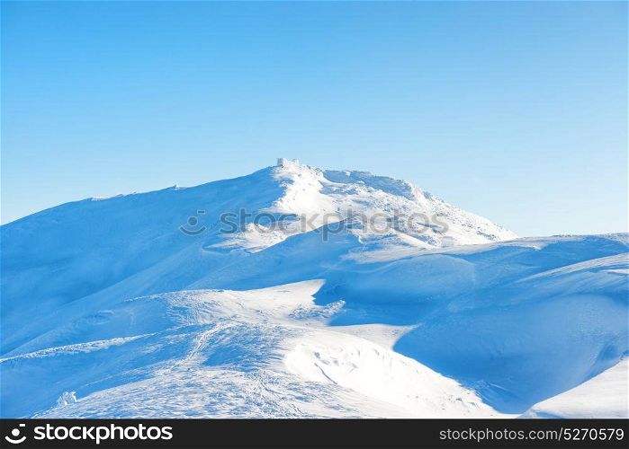 Winter landscape with old castle on top. Range of mountains peaks in snow