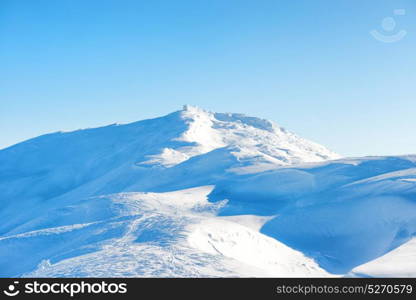 Winter landscape with old castle on top. Range of mountains peaks in snow