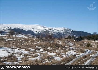 Winter landscape with rural road and snowy mountains in the distance