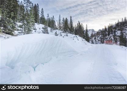 Winter landscape with snowy forest, snow-covered mountain road and the snowdrifts on the roadside. Alpine scenery in the nearby of the village Ehrwald, Austria