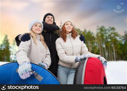 winter, leisure and entertainment concept - group of happy friends with snow tubes hugging over natural background. happy friends with snow tubes outdoors in winter