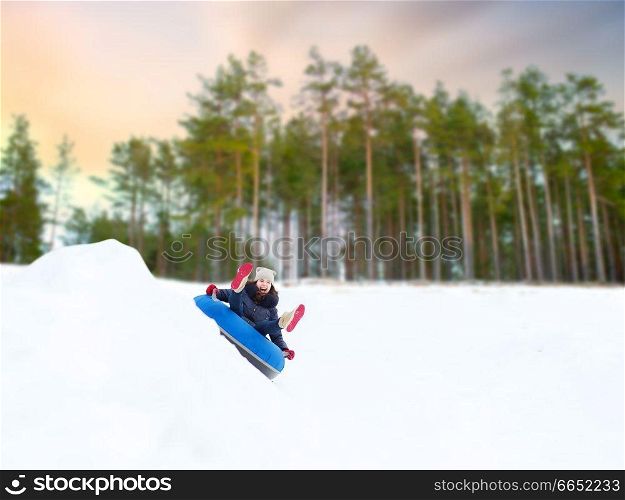 winter, leisure and entertainment concept - happy teenage girl sliding down hill on snow tube. happy teenage girl sliding down hill on snow tube