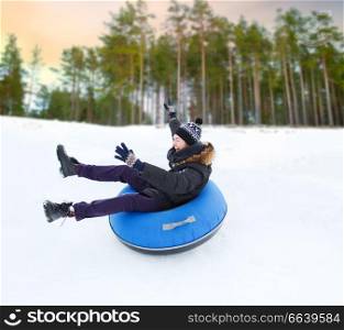 winter, leisure and entertainment concept - happy young man sliding down hill on snow tube over natural background. happy young man sliding down hill on snow tube