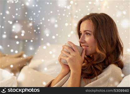 winter, leisure and people concept - happy young woman with cup of coffee or tea in bed at home over snow. happy woman with cup of coffee in bed at home
