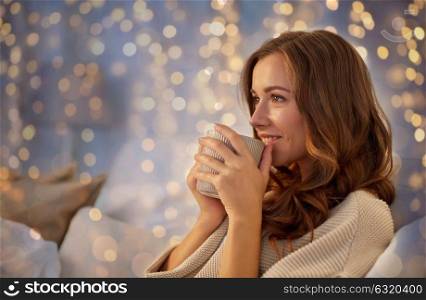 winter, leisure and people concept - happy young woman with cup of coffee or tea in bed at home bedroom. happy woman with cup of coffee in bed at home