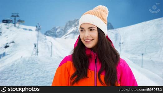 winter, leisure, clothing and people concept - happy young woman or teenage girl in winter clothes over downhill skiing and mountains background
