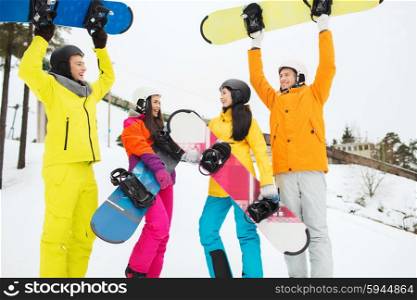 winter, leisure, extreme sport, friendship and people concept - happy friends in helmets with snowboards having fun outdoors