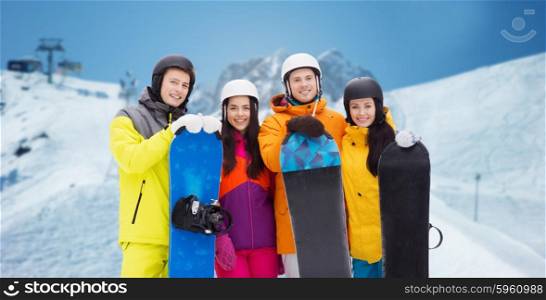 winter, leisure, extreme sport, friendship and people concept - happy friends in helmets with snowboards over downhill skiing and mountains background