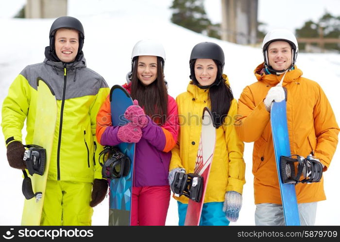 winter, leisure, extreme sport, friendship and people concept - happy friends in helmets with snowboards