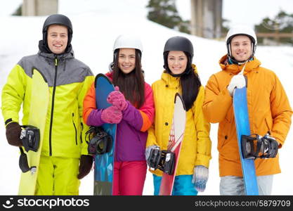 winter, leisure, extreme sport, friendship and people concept - happy friends in helmets with snowboards