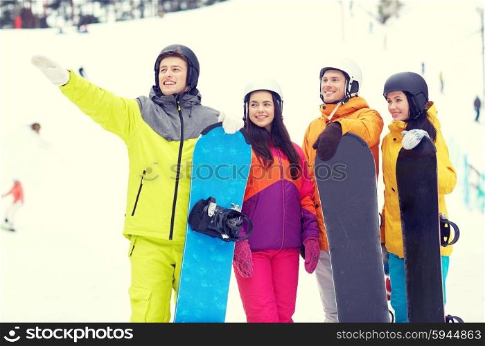 winter, leisure, extreme sport, friendship and people concept - happy friends in helmets with snowboards