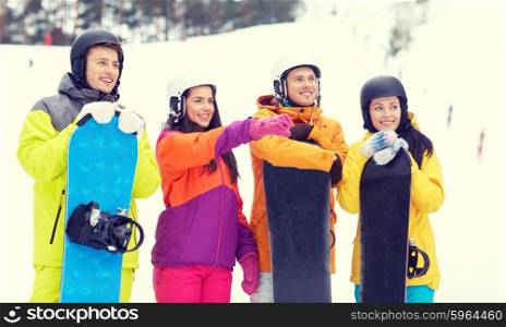 winter, leisure, extreme sport, friendship and people concept - happy friends in helmets with snowboards