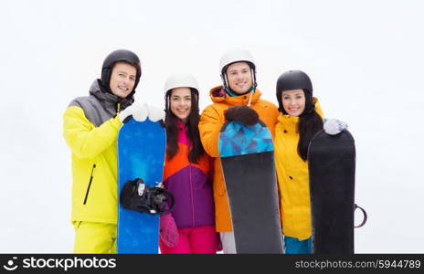 winter, leisure, extreme sport, friendship and people concept - happy friends in helmets with snowboards outdoors