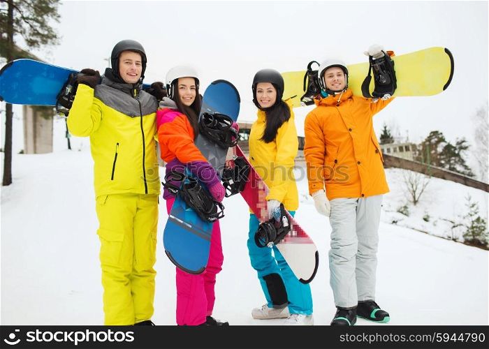 winter, leisure, extreme sport, friendship and people concept - happy friends in helmets with snowboards outdoors