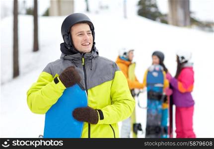 winter, leisure, extreme sport, friendship and people concept - happy young man in helmet with snowboard and group of friends