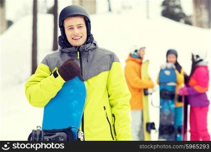 winter, leisure, extreme sport, friendship and people concept - happy young man in helmet with snowboard and group of friends