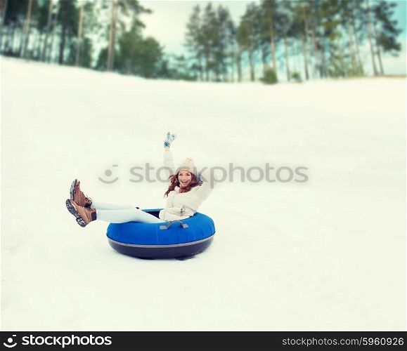 winter, leisure, sport, and people concept - happy teenage girl or woman sliding down on snow tube