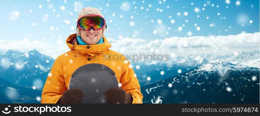winter, leisure, sport and people concept - happy young man in ski goggles over snowy mountain background