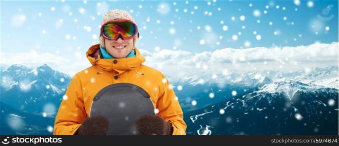 winter, leisure, sport and people concept - happy young man in ski goggles over snowy mountain background