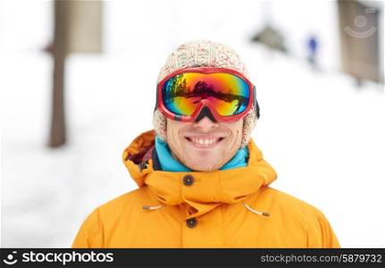 winter, leisure, sport and people concept - happy young man in ski goggles outdoors