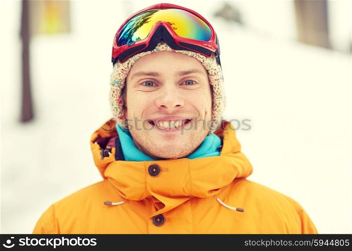 winter, leisure, sport and people concept - happy young man in ski goggles outdoors