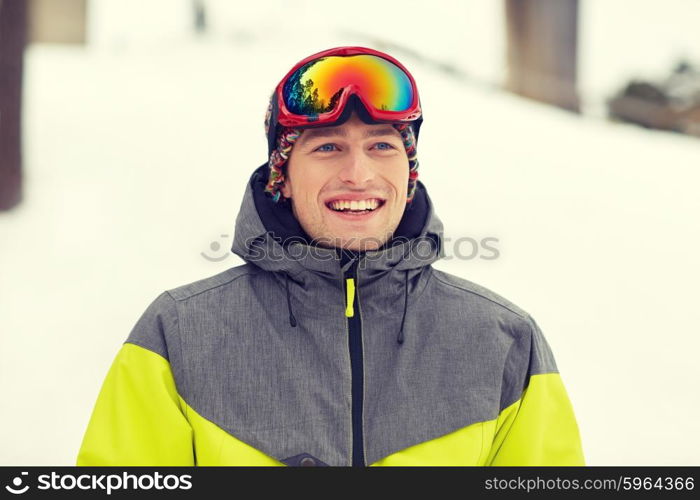 winter, leisure, sport and people concept - happy young man in ski goggles outdoors