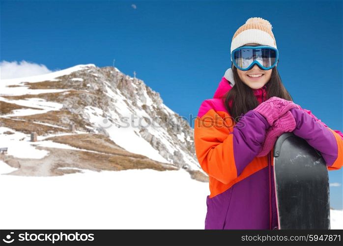 winter, leisure, sport and people concept - happy young woman in ski goggles with snowboard over snow and mountain background