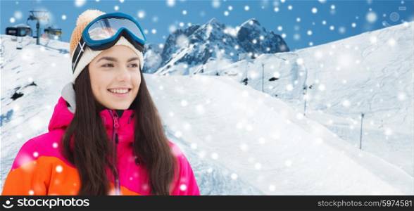 winter, leisure, sport and people concept - happy young woman in ski goggles over snow and mountain background
