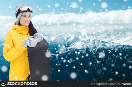 winter, leisure, sport and people concept - happy young woman in ski goggles with snowboard over snowy mountain background