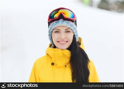 winter, leisure, sport and people concept - happy young woman in ski goggles outdoors