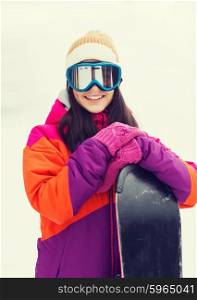 winter, leisure, sport and people concept - happy young woman in ski goggles with snowboard outdoors