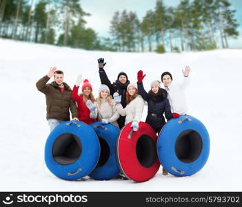 winter, leisure, sport, friendship and people concept - group of smiling friends with snow tubes waving hands outdoors