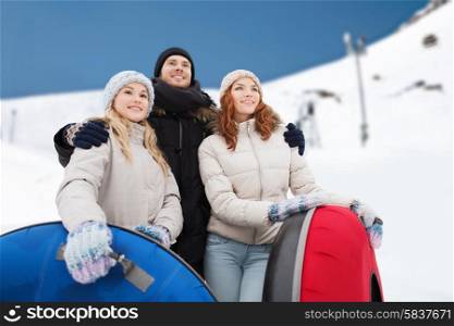 winter, leisure, sport, friendship and people concept - group of smiling friends with snow tubes over mountain background