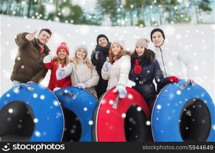 winter, leisure, sport, friendship and people concept - group of smiling friends with snow tubes showing thumbs up outdoors