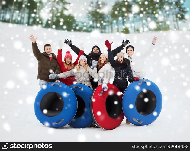 winter, leisure, sport, friendship and people concept - group of smiling friends with snow tubes waving hands outdoors