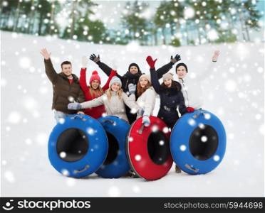 winter, leisure, sport, friendship and people concept - group of smiling friends with snow tubes waving hands outdoors