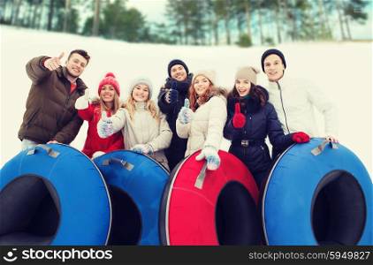 winter, leisure, sport, friendship and people concept - group of smiling friends with snow tubes showing thumbs up outdoors