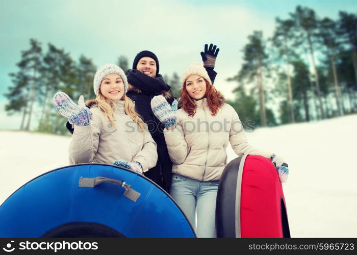 winter, leisure, sport, friendship and people concept - group of smiling friends with snow tubes waving hands outdoors