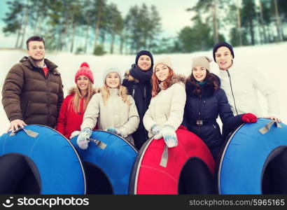winter, leisure, sport, friendship and people concept - group of smiling friends with snow tubes outdoors