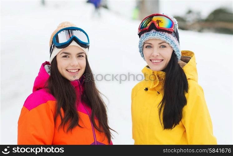 winter, leisure, sport, friendship and people concept - happy girl friends in ski goggles outdoors