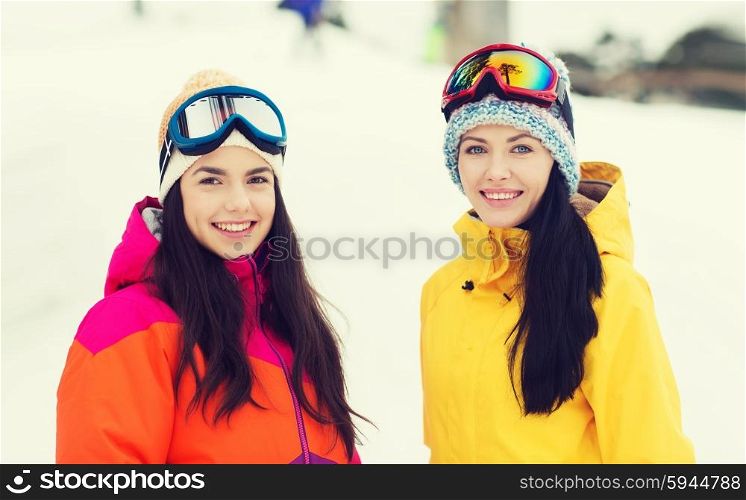 winter, leisure, sport, friendship and people concept - happy girl friends in ski goggles outdoors
