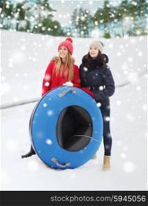 winter, leisure, sport, friendship and people concept - happy girl friends with snow tubes outdoors