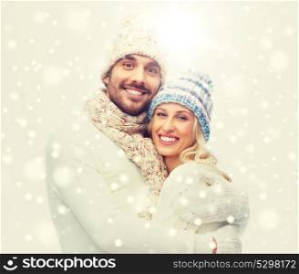 winter, love, couple, christmas and people concept - smiling man and woman in hats and scarf hugging. smiling couple in winter clothes hugging