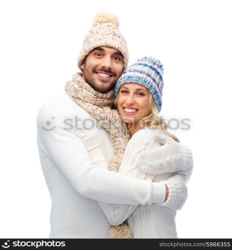 winter, love, couple, christmas and people concept - smiling man and woman in hats and scarf hugging