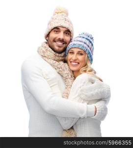 winter, love, couple, christmas and people concept - smiling man and woman in hats and scarf hugging